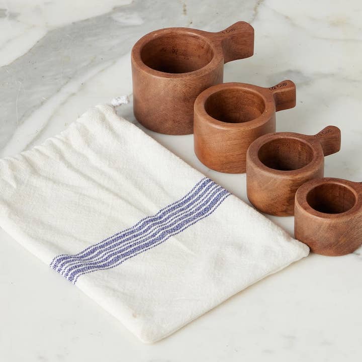 Set of wooden measuring cups on a white cloth with blue stripes