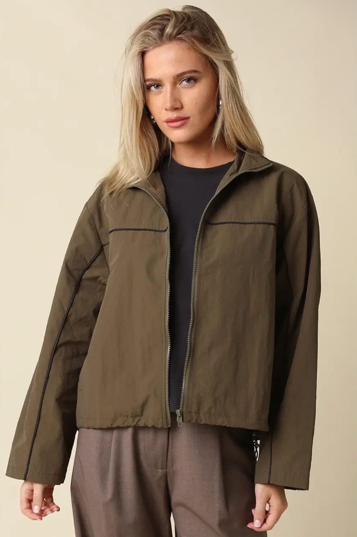 Alina olive zip-up jacket with black piping, open over a black tee