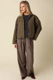 Woman wearing olive green Alina piped zip-up jacket with brown wide-leg trousers and burgundy loafers